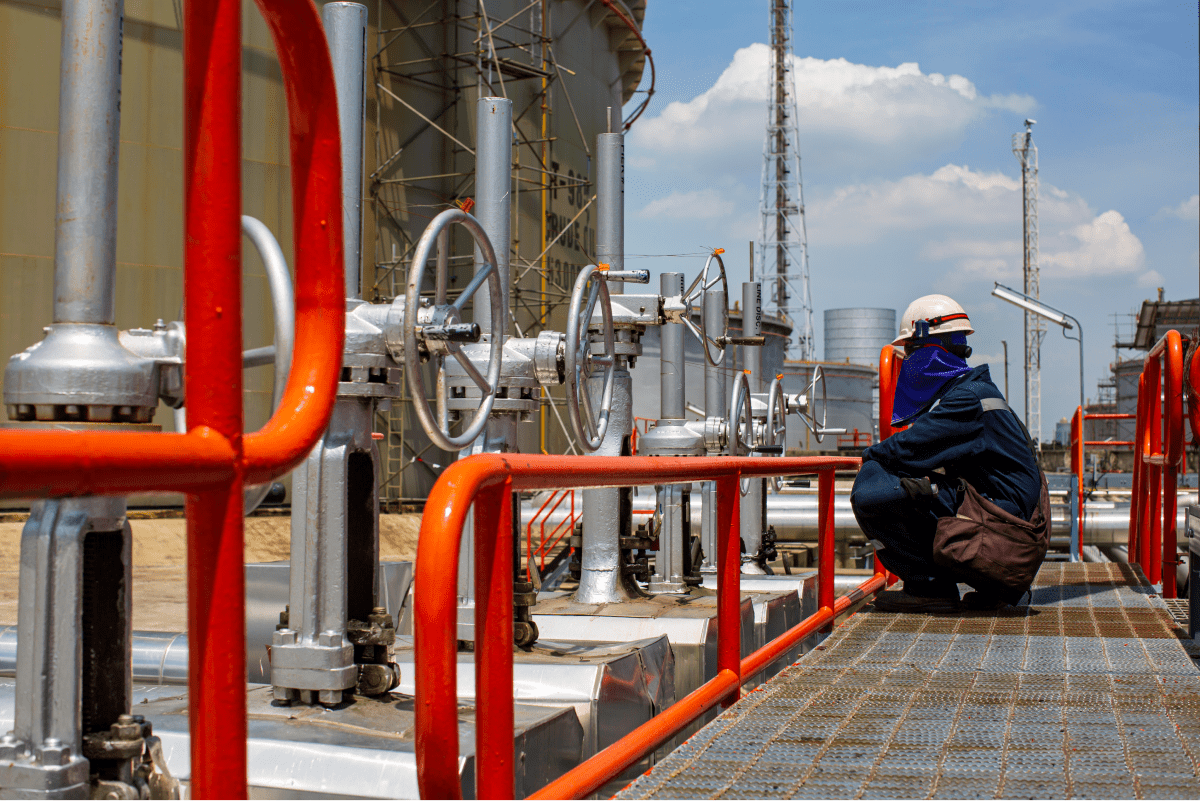 An oil refinery technician monitoring equipment, showcasing the meticulous care taken to ensure the smooth operation of refinery machinery.