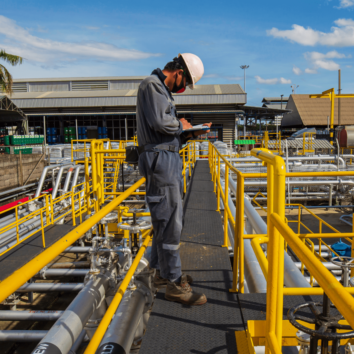 An oil refinery worker conducting inspections on a platform, emphasizing the importance of safety and maintenance in oil operations.